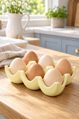 A pale yellow ceramic egg holder filled with brown and cream eggs, set on a wooden kitchen countertop with a blurred kitchen background.