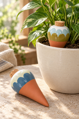 Set of two ceramic watering spikes for potted plants. Ana Blue includes complementary scalloped designs in blue, pale cream and olive, with white tops, terracotta-coloured tapered points and cork stoppers. 