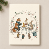 A vertical art print featuring a whimsical winter illustration of a fox, rabbit, mice, and a watering can at a small table under a holly arch, shown against a warm beige background with pine branches in the corner.