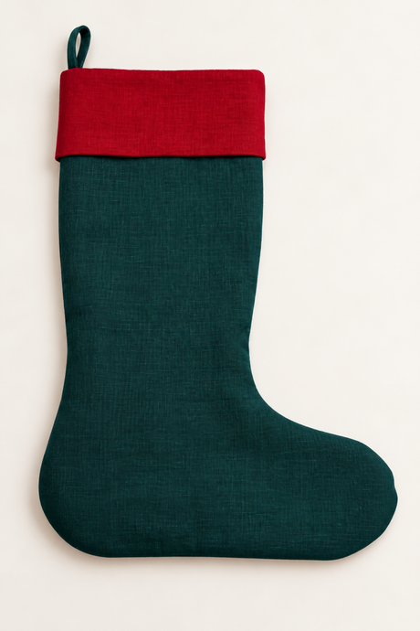 A dark green linen Christmas stocking with a contrasting red cuff and a hanging loop, shown against a plain off-white background.
