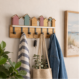a wooden coat rack with colourful beach houses and various items hanging on it.