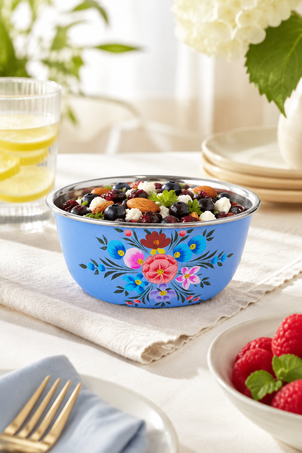 Decorative blue bowl with floral patterns filled with berries on a table setting.