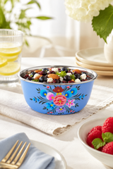 Decorative blue bowl with floral patterns filled with berries on a table setting.