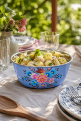 Decorative floral-patterned bowl filled with salad on a table outdoors.