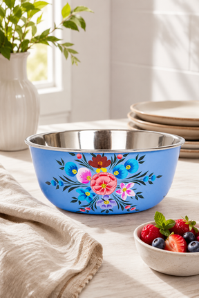 Blue floral-patterned bowl on a table with a stack of plates and a bowl of berries in the background.