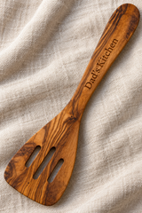 Personalised olive wood spatula engraved “Flipping Lovely”, beside a pan of courgettes, peppers and mushrooms.