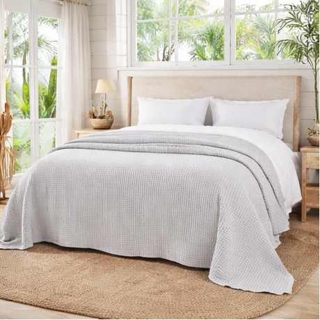 bed room with dove grey bed throw big open windows with plants outside
