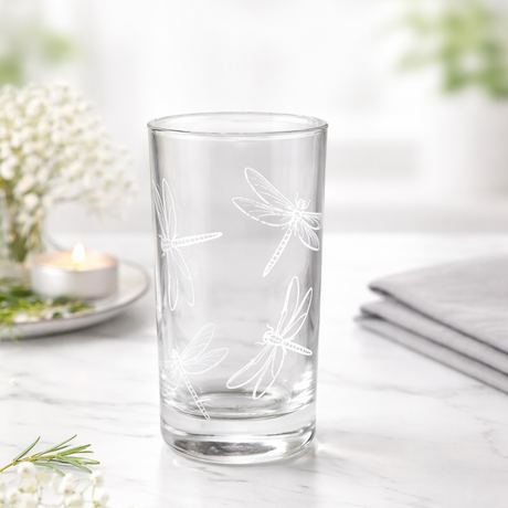 Clear glass with white floral design on a light wooden surface with blurred background