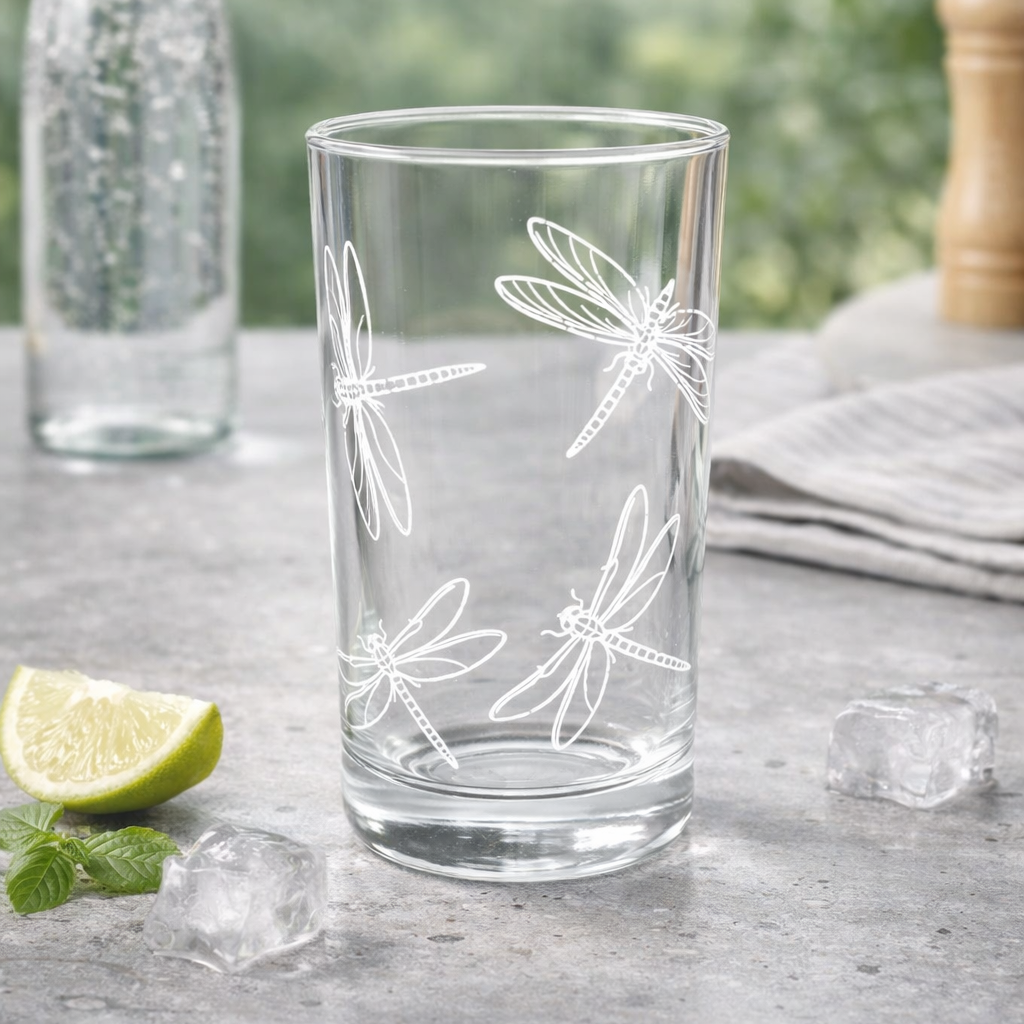 Clear glass with dragonfly design on a table with lime and ice cubes
