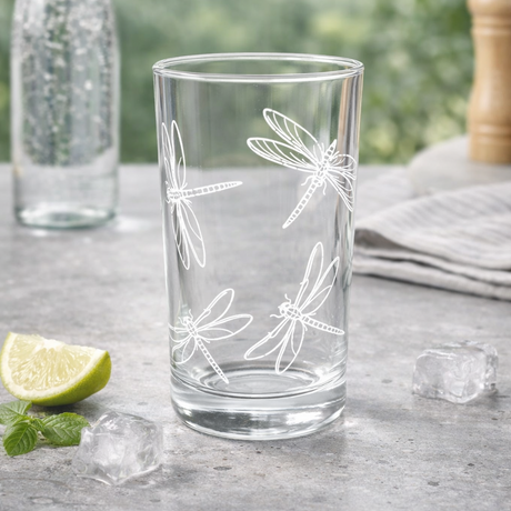 Clear glass with dragonfly design on a table with lime and ice cubes