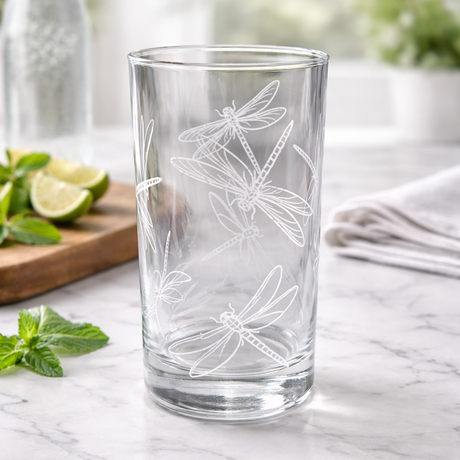 Clear glass with dragonfly design on a marble surface with limes and mint leaves.