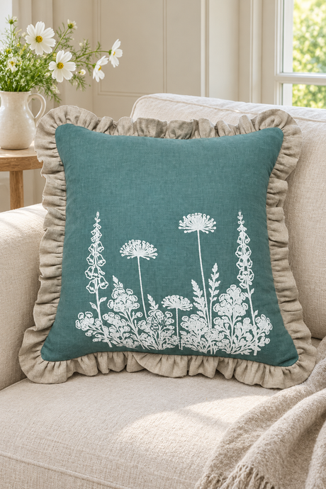 Square duck egg Florilegium cushion with white botanical flowers and a natural ruffle on an ivory sofa.