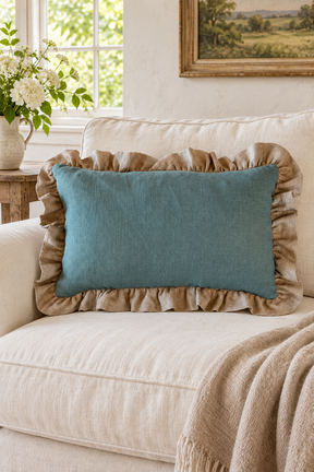 Plain rectangular duck egg linen cushion with a large natural ruffle on a cream sofa beside a flax throw.