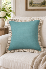 Square plain duck egg linen cushion with a large natural ruffle on a cream sofa.