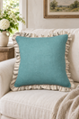 Square plain duck egg linen cushion with a large natural ruffle on a cream sofa.