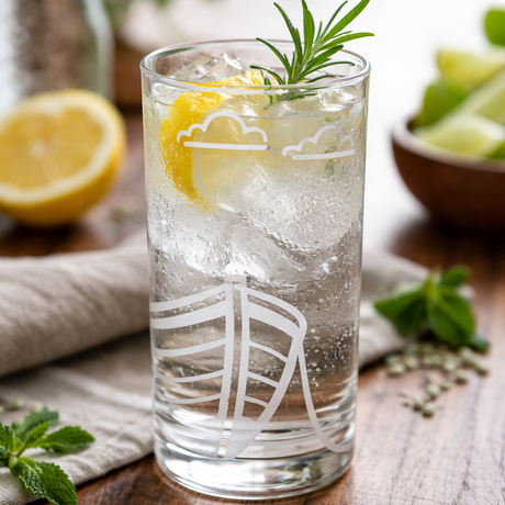 etched FJAERE boat design on Glass of iced drink with lemon and rosemary on a wooden table