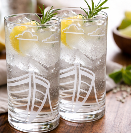 two FJAERE Boat Etched Glass Tumblers with lemon and rosemary on a wooden surface.