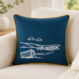 Fjære hand printed linen cushion cover in deep blue with white coastal boat design and mustard piping on a sofa.
