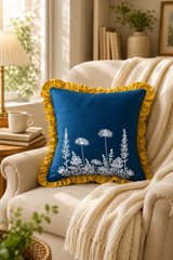 Decorative pillow with floral design on a beige armchair in a cozy living room. Florilegium Blue Ruffle Linen Cushion Cover – 55cm x 55cm