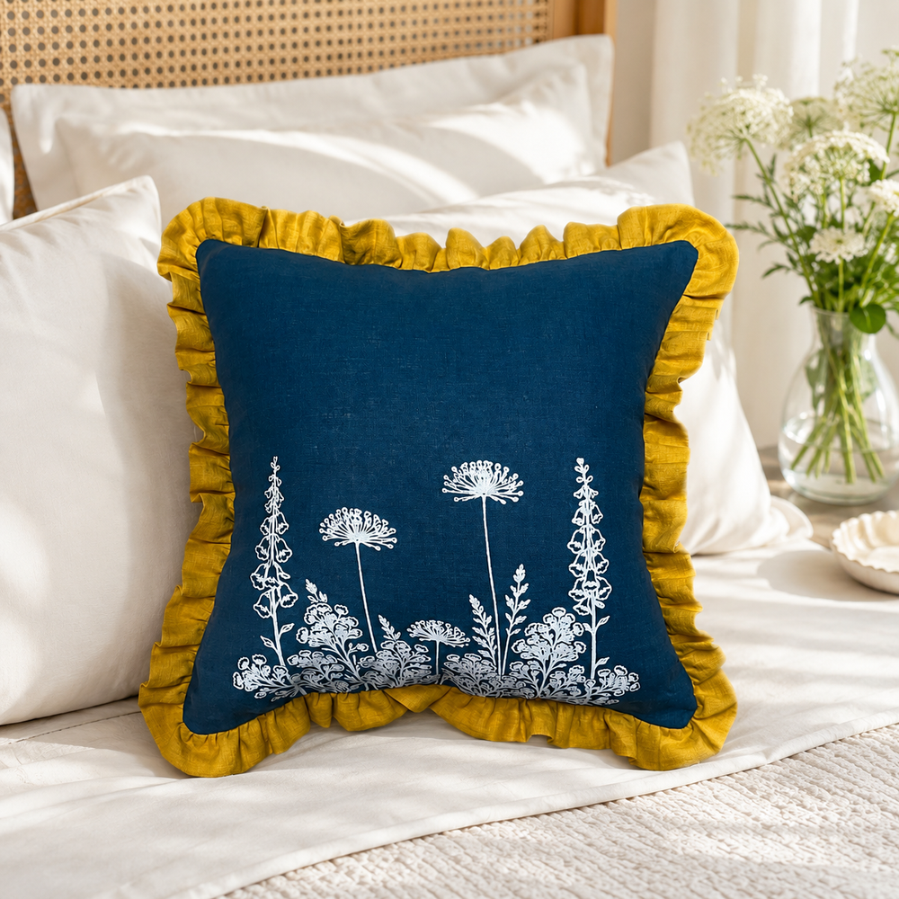 Florilegium blue linen cushion cover with white botanical print and mustard ruffle edge styled on a bed.