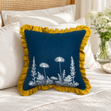 Florilegium blue linen cushion cover with white botanical print and mustard ruffle edge styled on a bed.