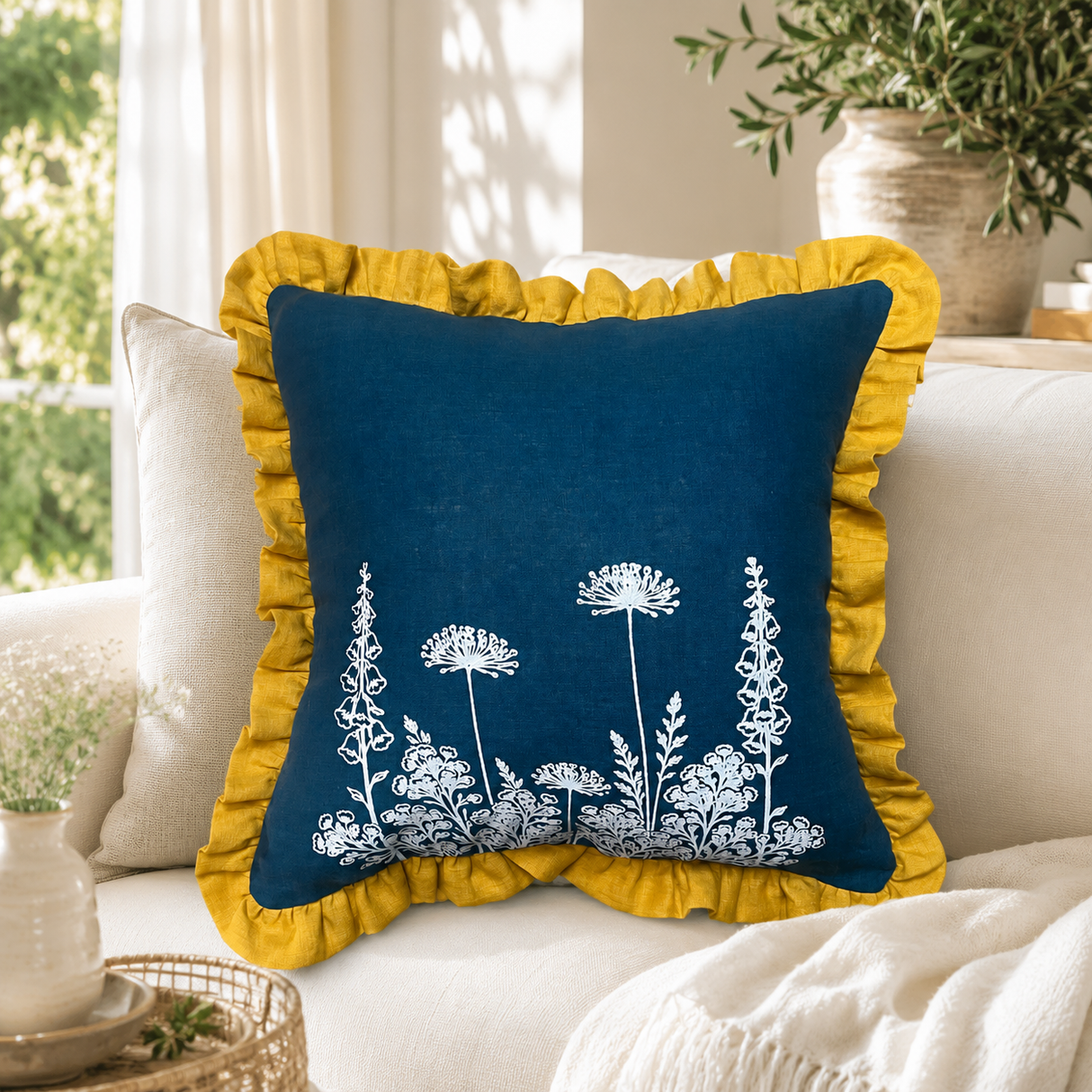 Florilegium blue linen cushion cover with white botanical print and mustard ruffle edge styled on a sofa.