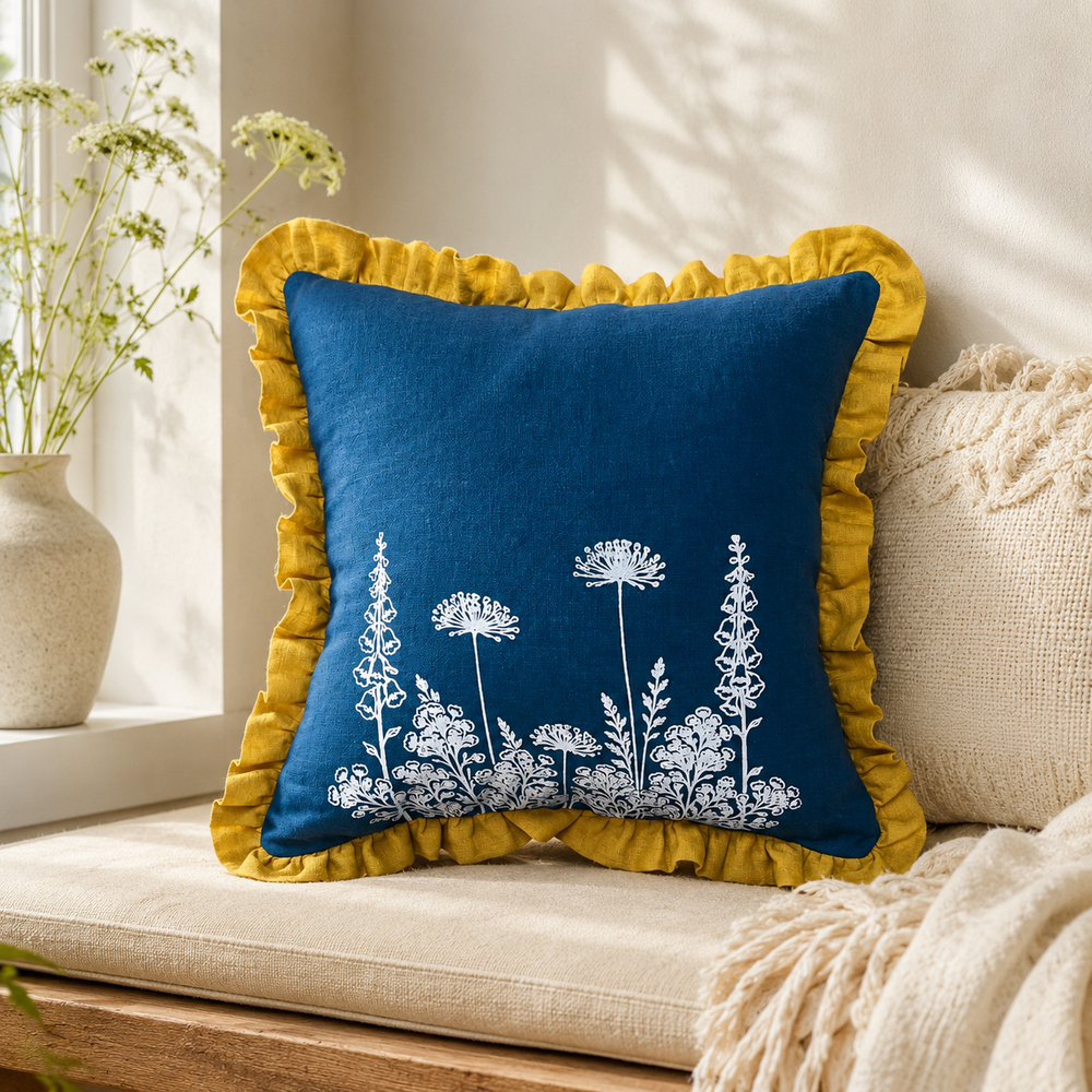Florilegium blue linen cushion cover with white botanical print and mustard ruffle edge styled on a window seat.