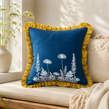 Florilegium blue linen cushion cover with white botanical print and mustard ruffle edge styled on a window seat.