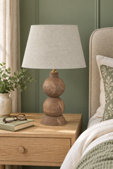 Frampton Medium brown mango wood table lamp with beige linen shade on a bedside table