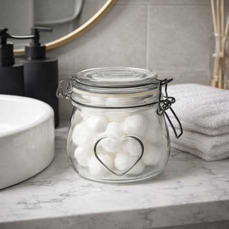 Glass jar with heart-shaped design on a bathroom counter