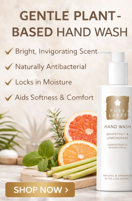 Pure Lakes hand wash bottle with grapefruit and lemongrass on a wooden board, surrounded by greenery.
