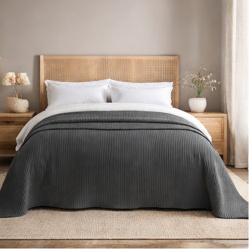 Grey quilt draped over a bed in bedroom setting.