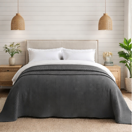 Grey quilt draped over a bed in bedroom setting.