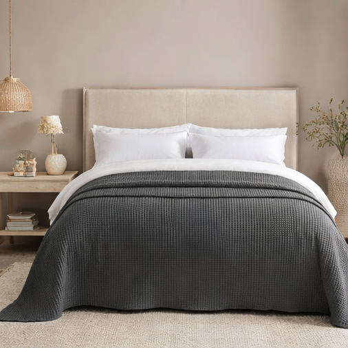 Grey quilt draped over a bed in bedroom setting.