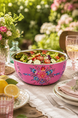 Pink floral-patterned bowl filled with salad on a table outdoors.