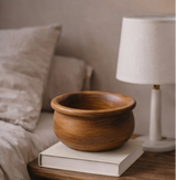 Wooden bowl on a stack of books with a lamp in the background