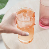 Hand holding a glass of pink iced drink with a blurred background