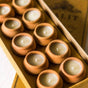 Set of small terracotta candles in a box with a brand name on the lid.