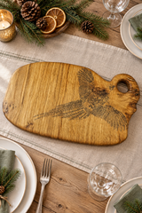 Wooden cutting board with engraved pheasant design and a tag on a white background