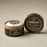 Handmade soap Keira scented in a round container with a label on a beige background
