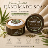 Handmade soap with Kevra scent, displayed with green leaves and a bowl of herbs on a neutral background.