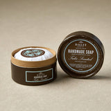 Handmade soap tulsi scented in a brown container with a visible label on a beige background
