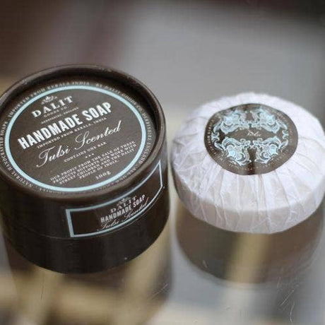 Handmade soap in a black container and white bar on a reflective surface