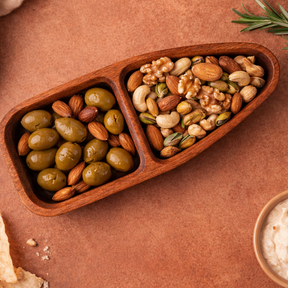 Wooden tray with compartments filled with olives and nuts on a brown surface