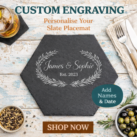 Hexagonal slate placemat with engraved names and date on a rustic wooden table with dining items.