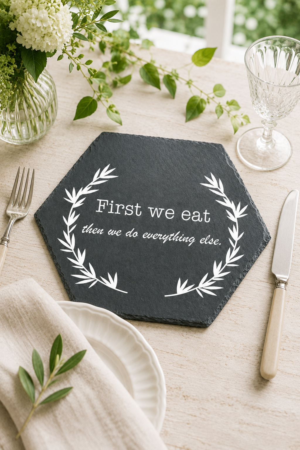 Hexagonal slate placemat with engraved quote on a table setting with flowers and cutlery.