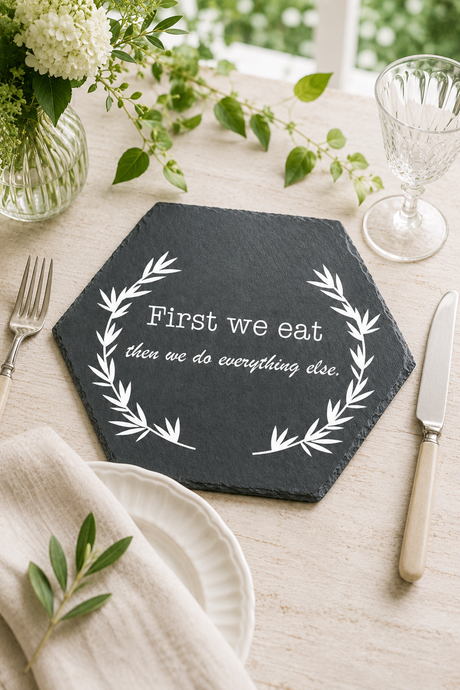 Hexagonal slate placemat with engraved quote on a table setting with flowers and cutlery.