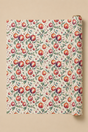 A roll of wrapping paper with a Holly & Bauble Christmas Watercolour paten, partially unrolled to show the repeating print on a solid beige background.