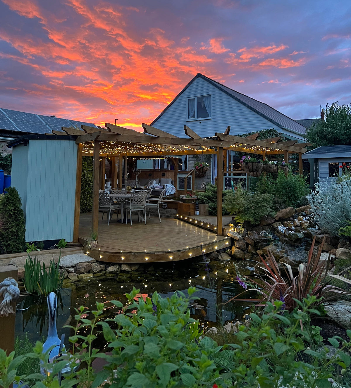 Sunset over a house with a pond deck and garden