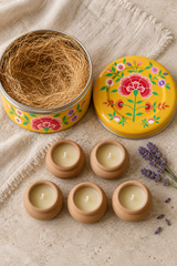 Gift set containing five hand-poured beeswax-blend candles in handmade terracotta pots and one reusable yellow stainless steel tin. The round tin is hand-painted in Kashmir with multicoloured floral decoration.
